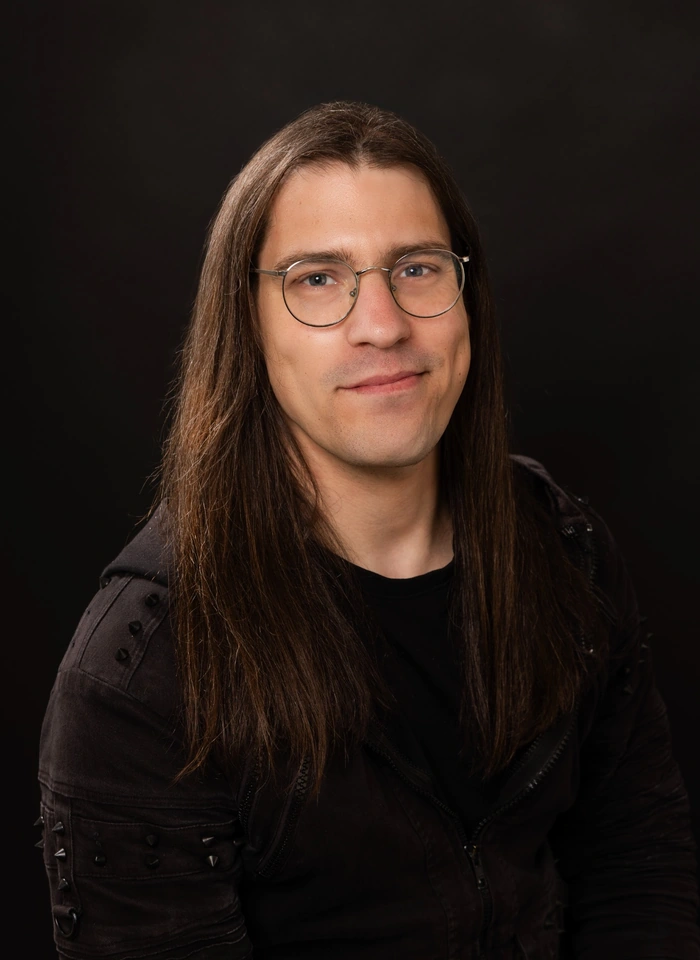 Lucas Walz, Porträt mit langem braunem Haar und Brille